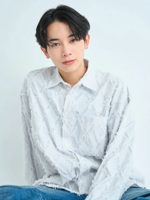 フリンジ加工の白いシャツを着た島村雄大さんのポートレート