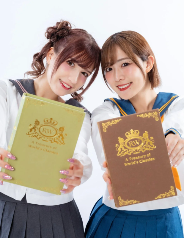 セーラー服を着た二人の女性が笑顔で本を掲げる