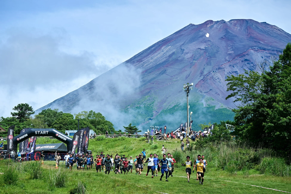 富士山を背景に、大勢の参加者がスパルタンレースのスタートラインから一斉に走り出す様子