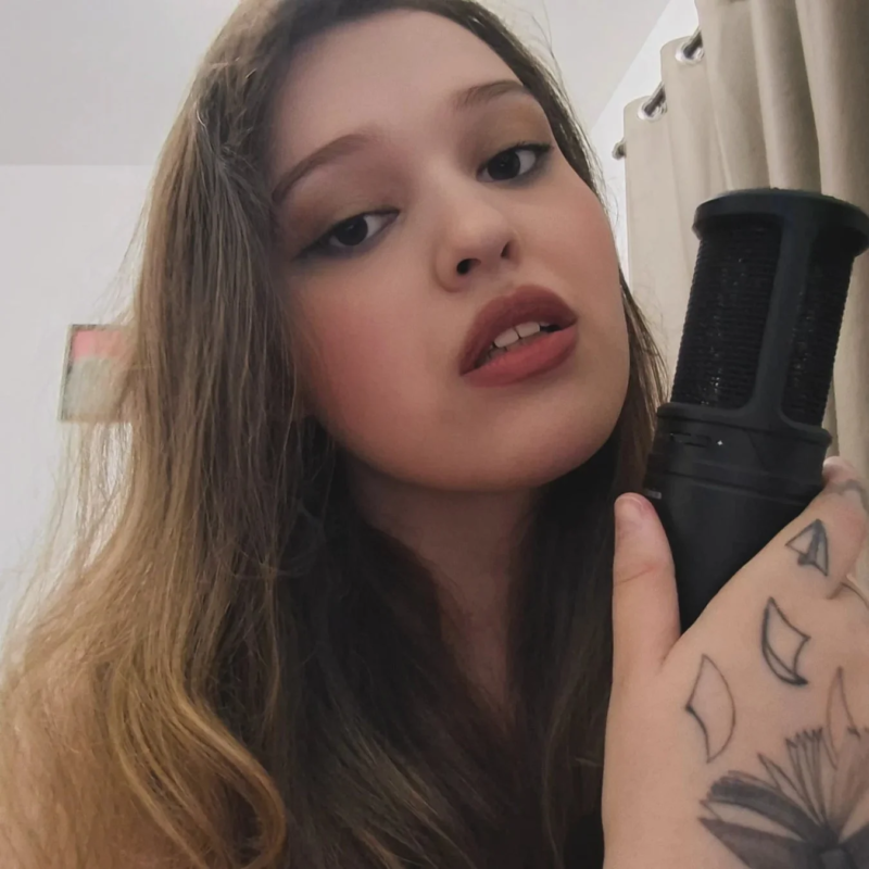 マイクを手に持ち、カメラを見つめる若い女性のクローズアップポートレート