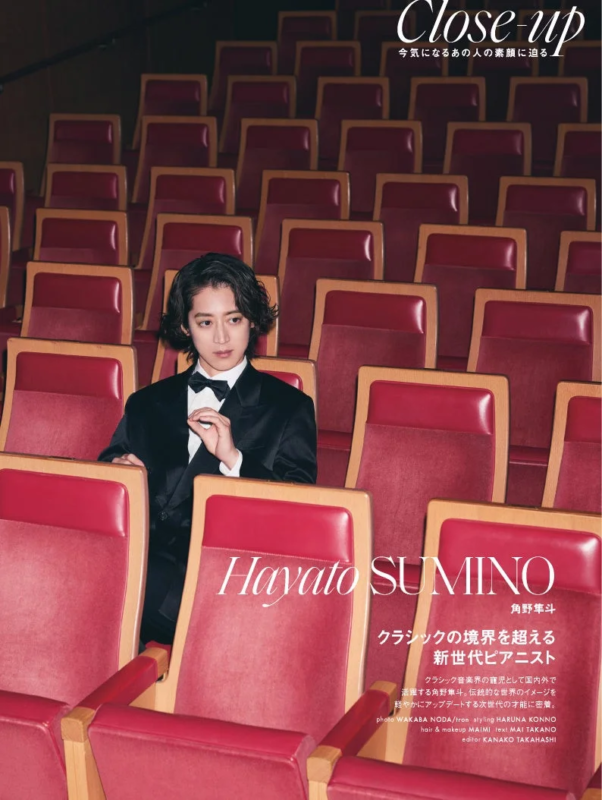 劇場のような赤い座席に座るタキシード姿のピアニスト角野隼斗のポートレート。クラシックの境界を超える新世代ピアニストとして紹介されており、雑誌のクローズアップ記事の一部。