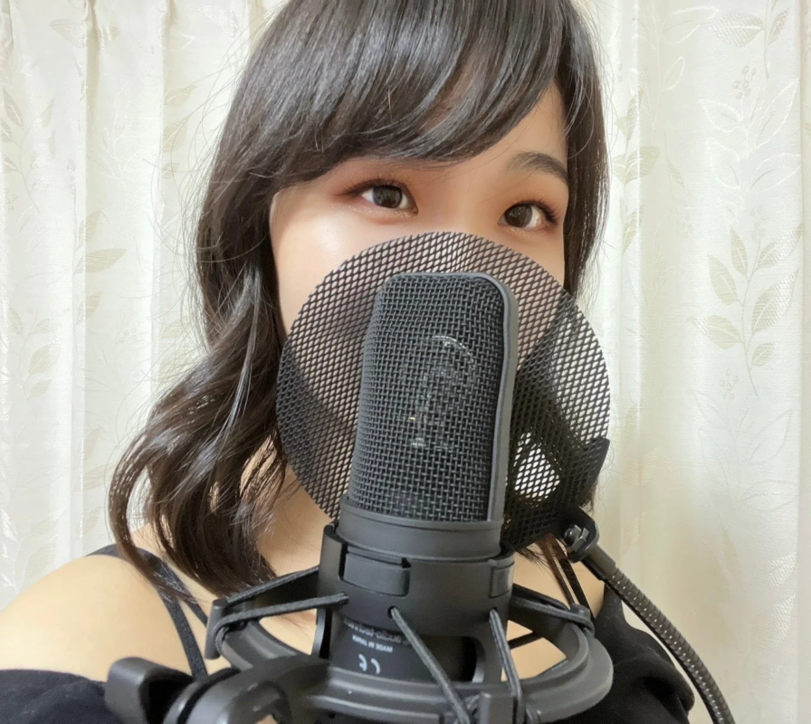 女性がマイクの前に立って歌っている様子