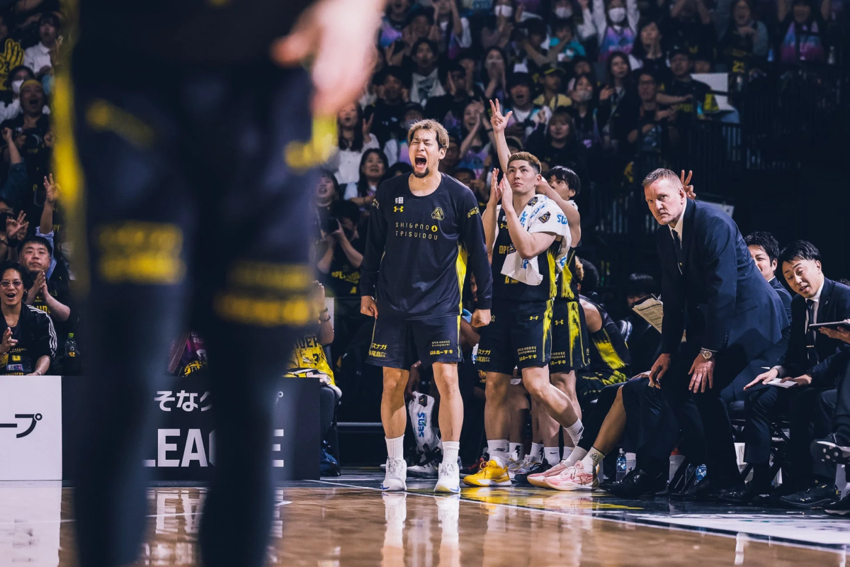 バスケットボールの試合中、ベンチの選手たちが激しく感情を露わにしている