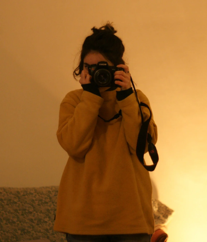 黄色いトップスを着た人物が、SONYのカメラを構えて鏡越しに自撮りをしている様子