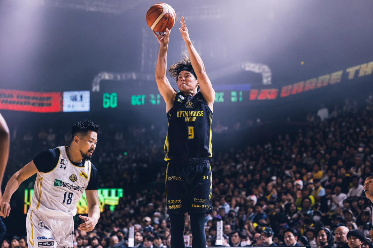 バスケットボールの試合で、黒いユニフォームを着た選手がシュートを打つ瞬間