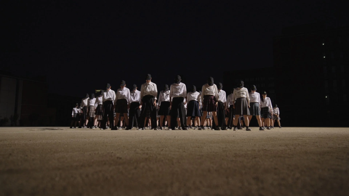 夜のグラウンドで制服の学生が整列している様子