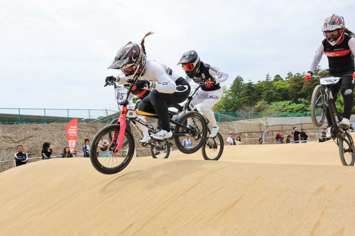 BMXレースで選手たちがダートコースのコブをジャンプ
