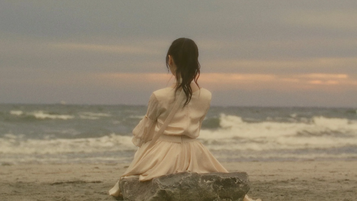 夕暮れのビーチで海を眺める石田千穂さんの後ろ姿