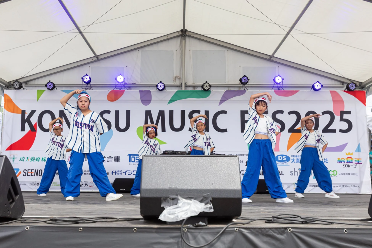 「KONOSU MUSIC FES2025」のバナーがある野外ステージで、複数の子供たちがヒップホップダンスを披露している