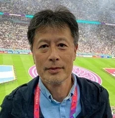 サッカースタジアムを背景に、カメラを見つめる中年男性のポートレート