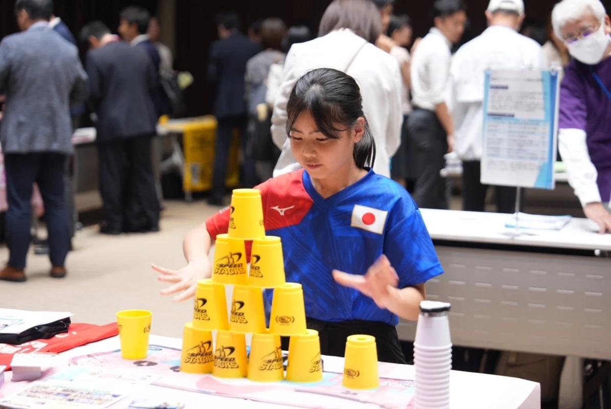 日本のユニフォームを着た少女がスポーツスタッキングに集中