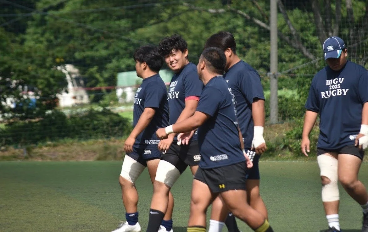緑のグラウンドを歩くラグビー選手たち