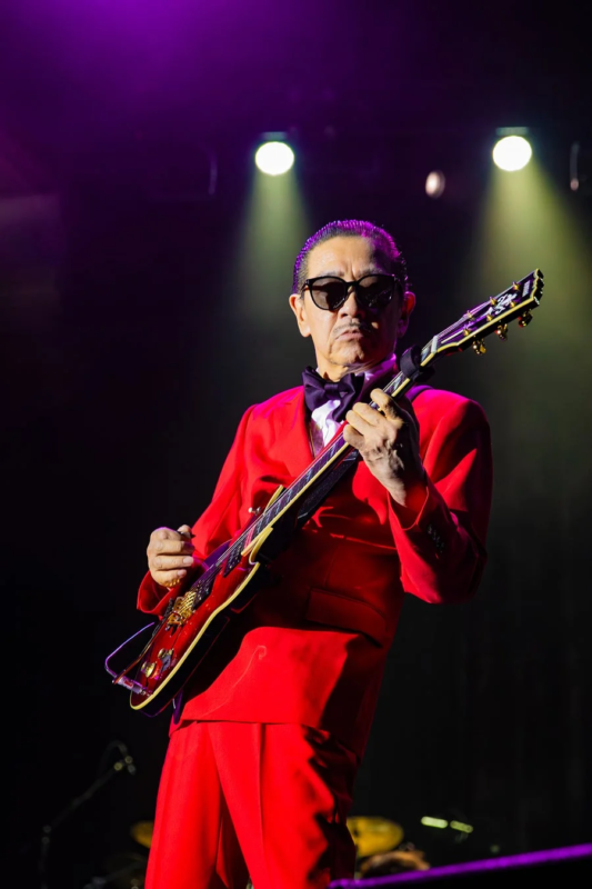 赤いスーツとサングラスでギターを演奏する高中正義さん