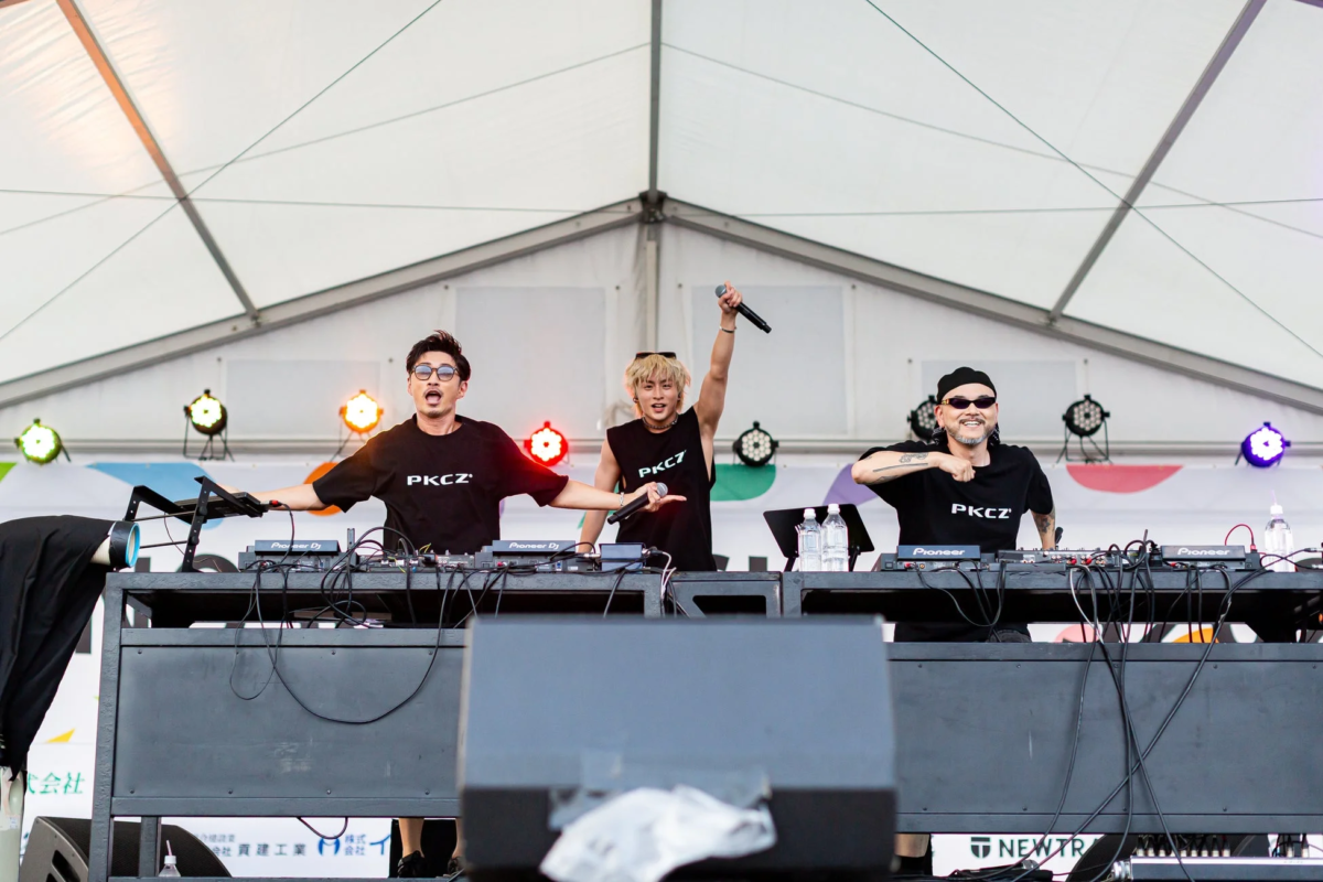 3人の男性グループPKCZがステージでDJパフォーマンスを行っている様子