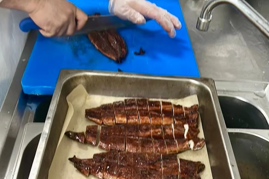 調理場で焼き魚を切る様子