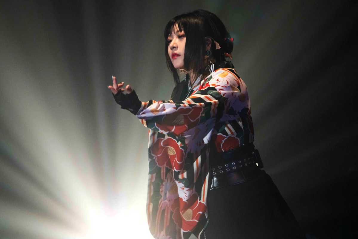 華やかな花柄の着物風衣装をまとった女性が、ステージ上でパフォーマンス