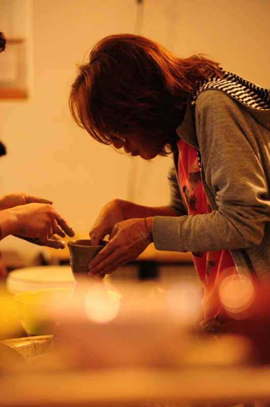 女性が集中して粘土をこね陶芸作品を制作している