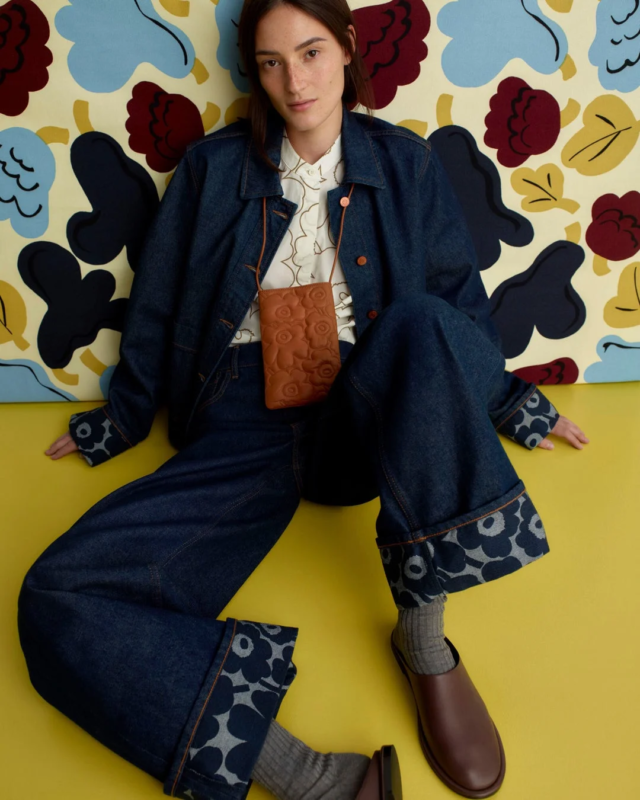デニムのセットアップと花柄シャツを着用し座る女性