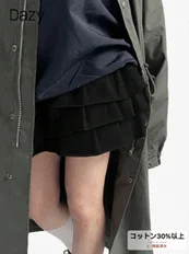 暗い色のロングコートと黒いフリル付きショートパンツを着用した人物