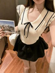 白いセーラー襟のニットトップスと黒いミニスカートを着用した女性