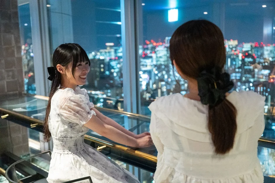 夜景を背景に会話する女性たち