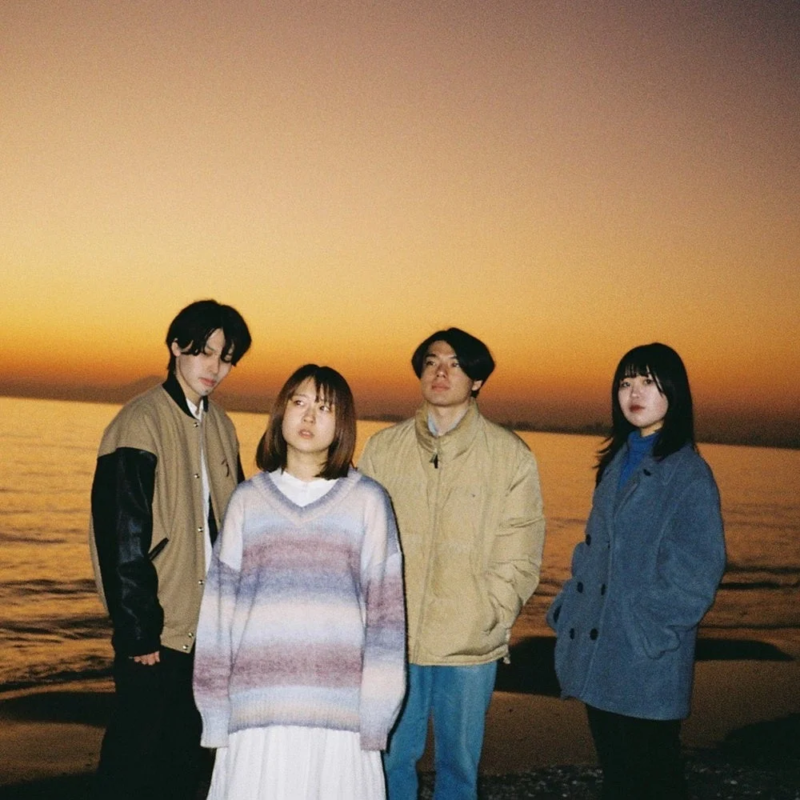 夕焼けの海辺に立つ4人組